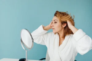 Woman arranging her short hair while looking into a mirror