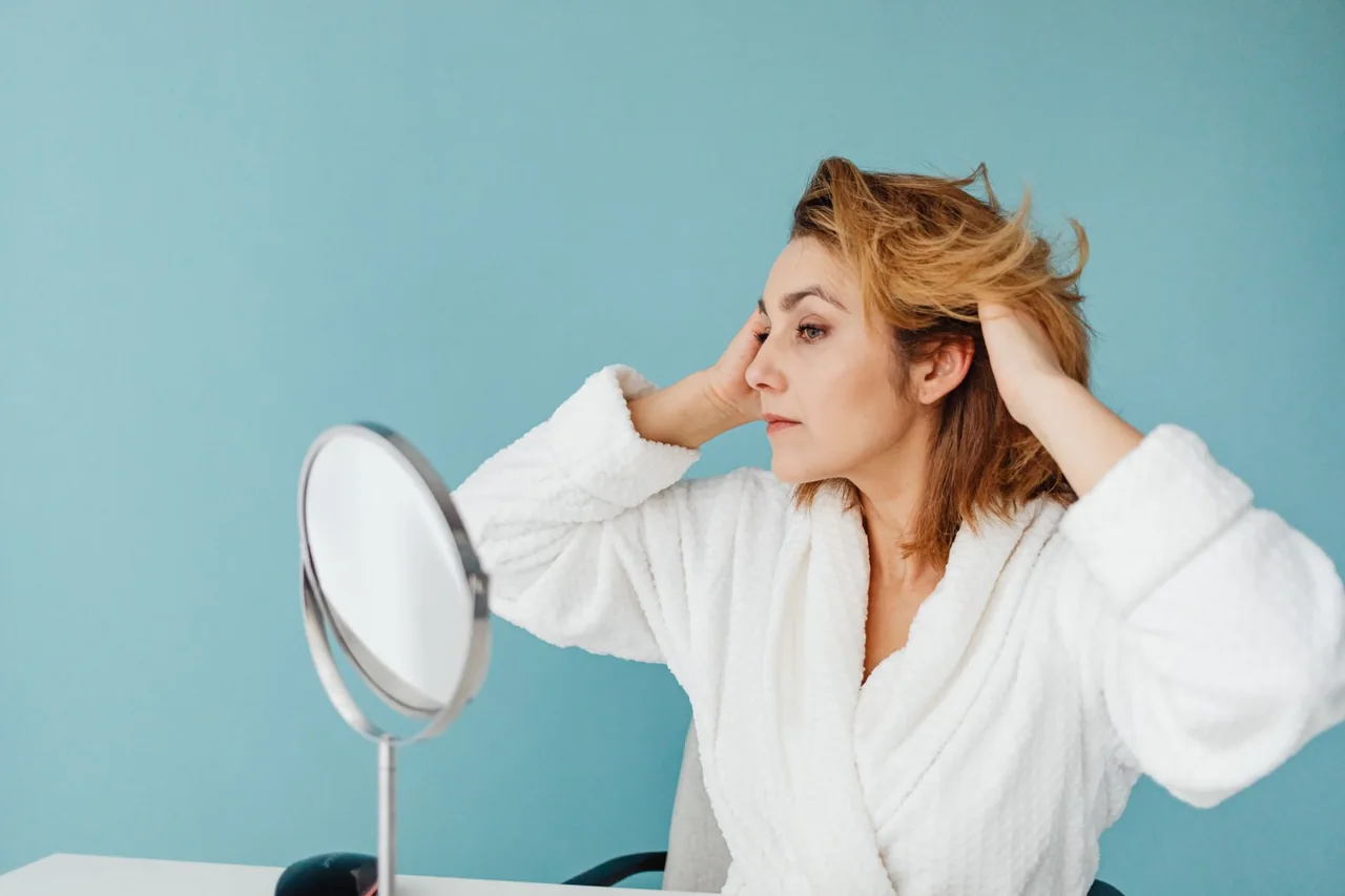 Woman arranging her short hair while looking into a mirror