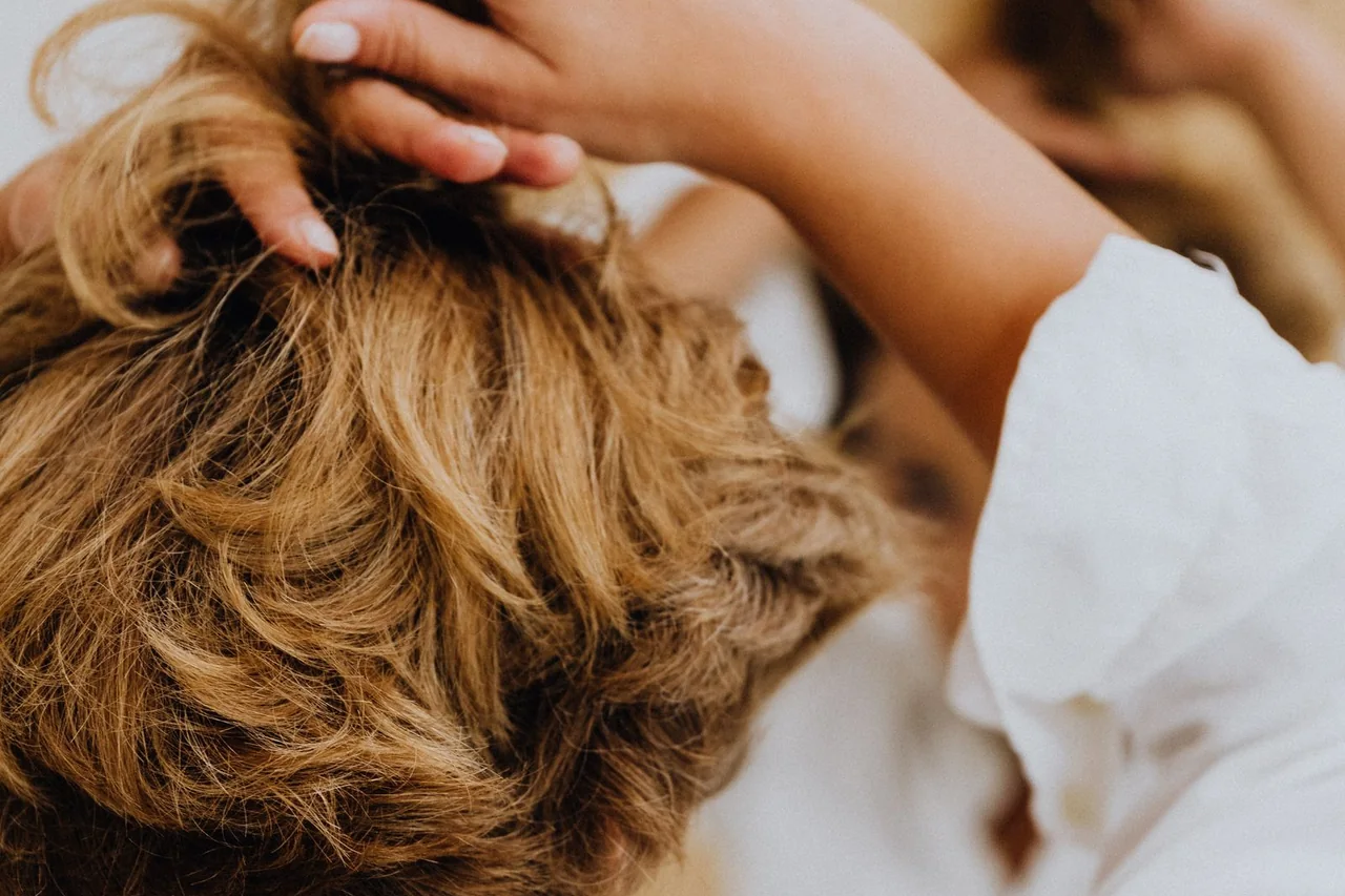 Back view of a woman gently lifting and arranging her short hair