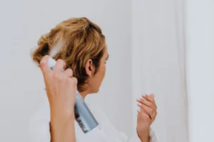 Woman applying a light hair spray to her short hair