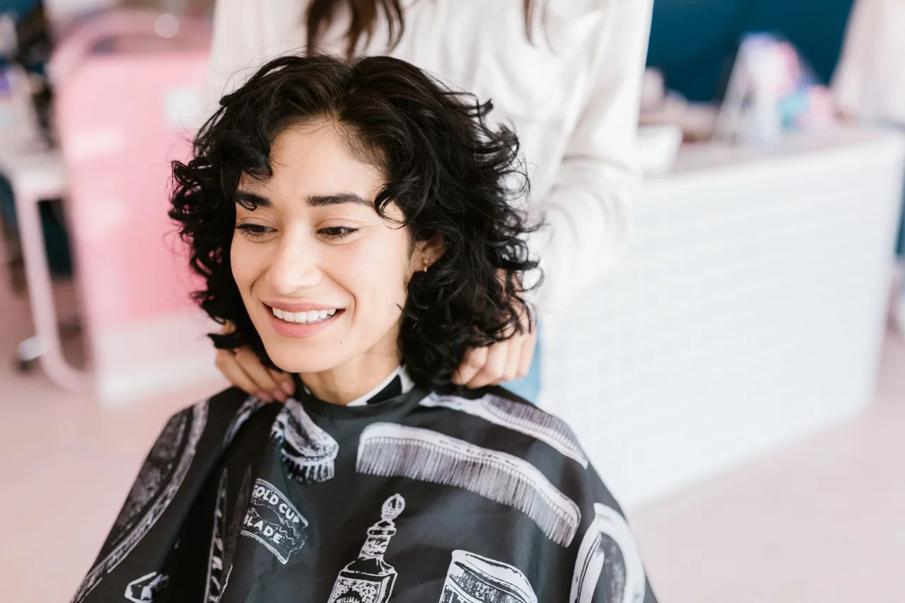 Woman with short curly hair smiling during a salon appointment