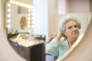 Mature woman checking her short grey hair in a salon mirror