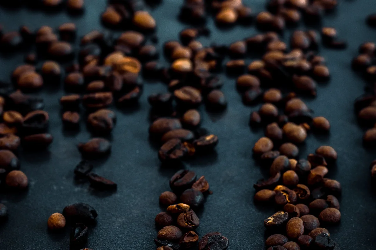 Roasted coffee beans scattered across a dark surface
