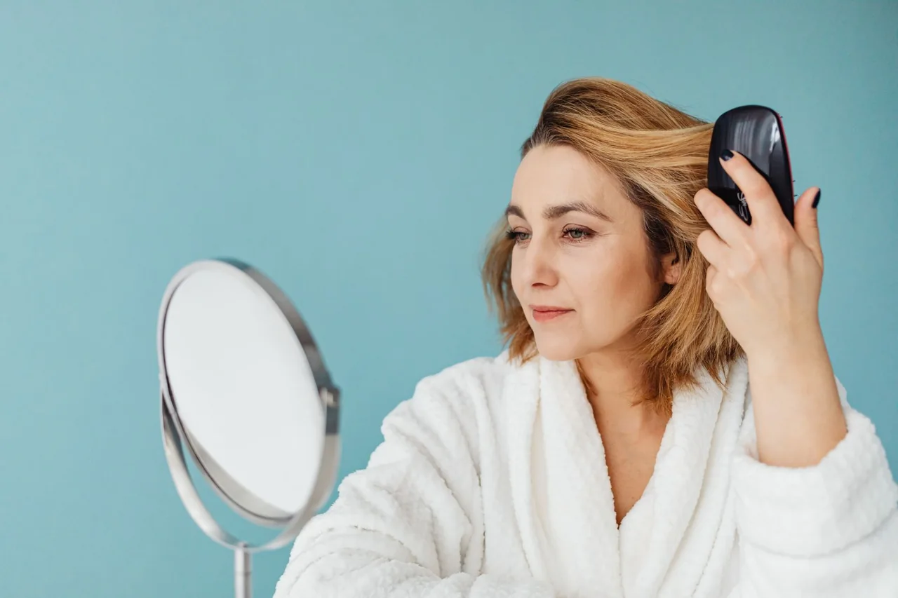 Woman following a simple hair-brushing routine in front of a mirror