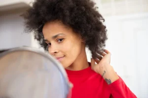 Woman looking into a mirror while arranging her natural curls